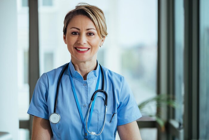 Portrait of smiling nurse looking at camera while standing at clinic