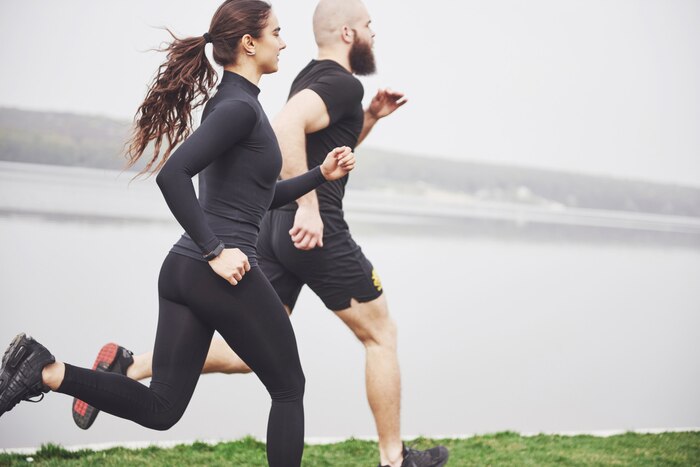 Couple jogging and running outdoors in park near the water. young bearded man and woman exercising together in morning
