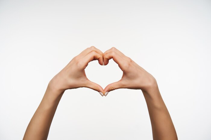Close up on pretty female\'s hands folding together heart sign