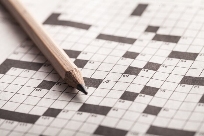 Crossword puzzle and pencil on background