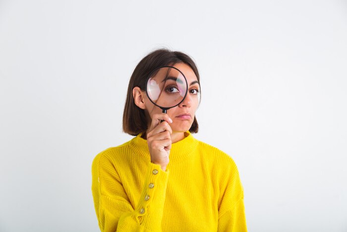 Pretty woman in yellow sweater on white  held magnifier happy positive playful