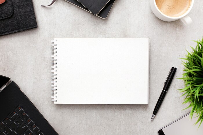 Blank notepad or notebook on workspace with office supplies, top view