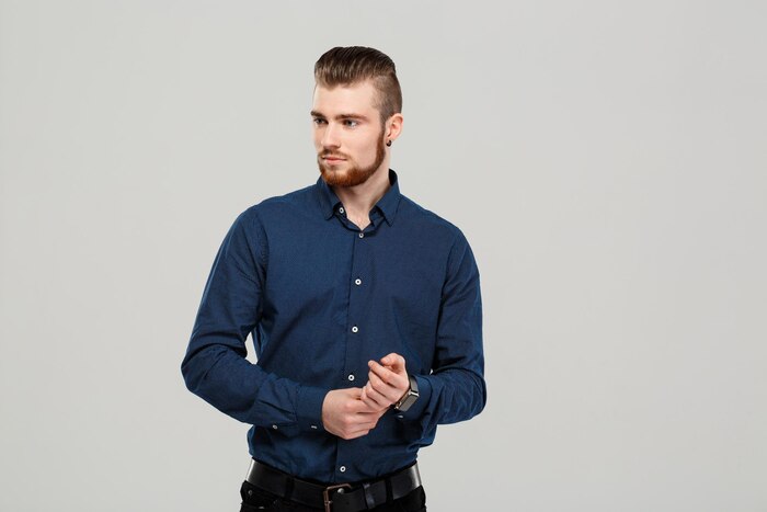 Young successful confident businessman posing, looking aside over grey wall