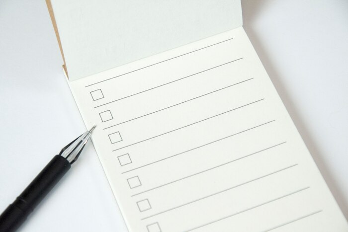 Blank to do list planner with checklist and black pen on white background, close up
