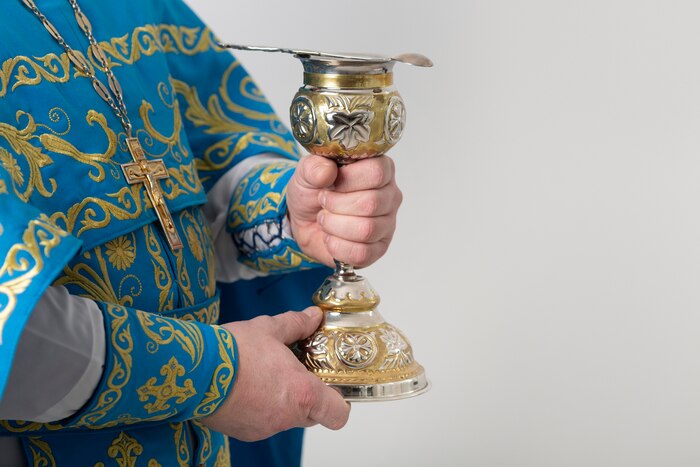 Holy communion concept with priest holding cup